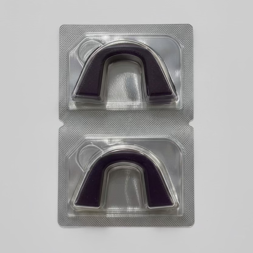 Two semi-custom teeth whitening trays in a clear plastic packaging on a textured surface.