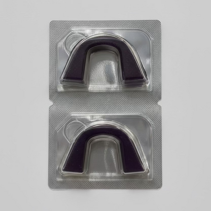 Two semi-custom teeth whitening trays in a clear plastic packaging on a textured surface.