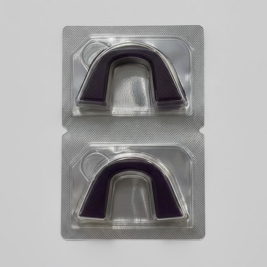 Two semi-custom teeth whitening trays in a clear plastic packaging on a textured surface.